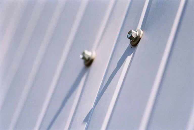 Roofing inspector verifying rubber gasket compression on metal panel fasteners